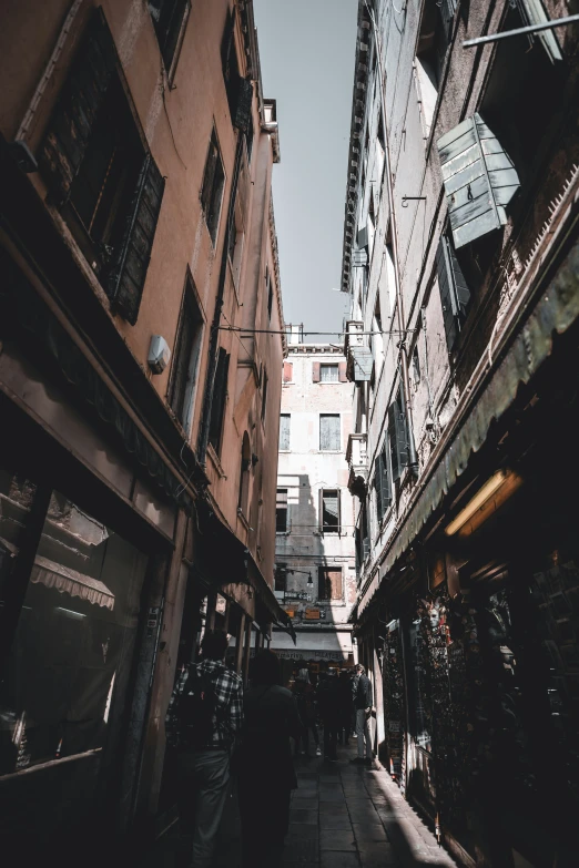 several people walking down the sidewalk in an alleyway