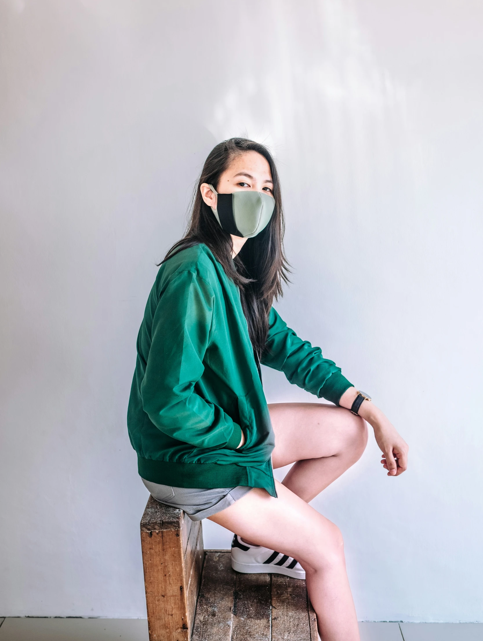 a woman sitting on a stool wearing a mask