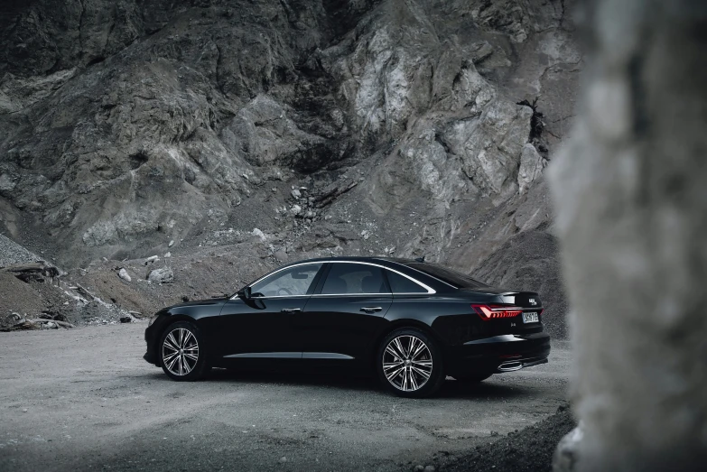 an elegant car sits on the side of a mountainous road