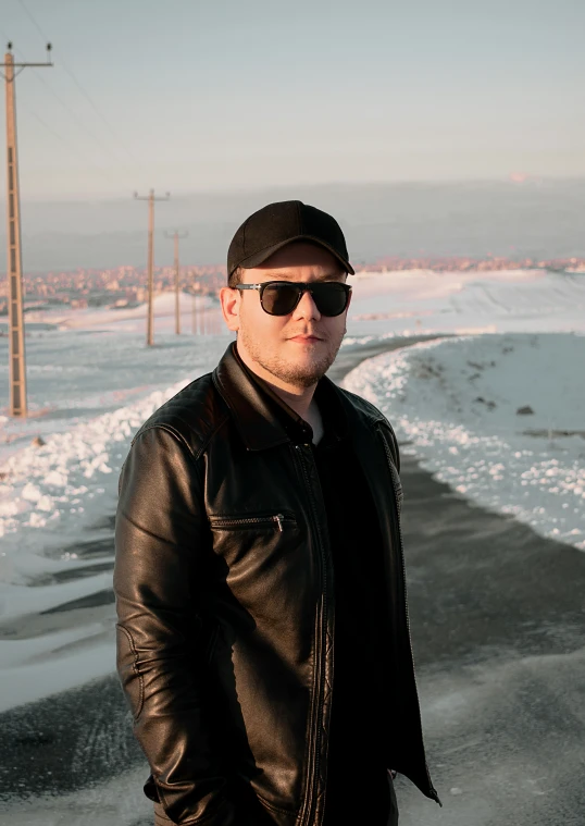 man in hat and sunglasses standing on sidewalk with snow