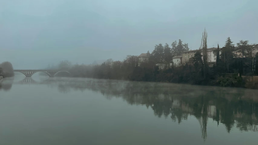 foggy river with houses in the distance