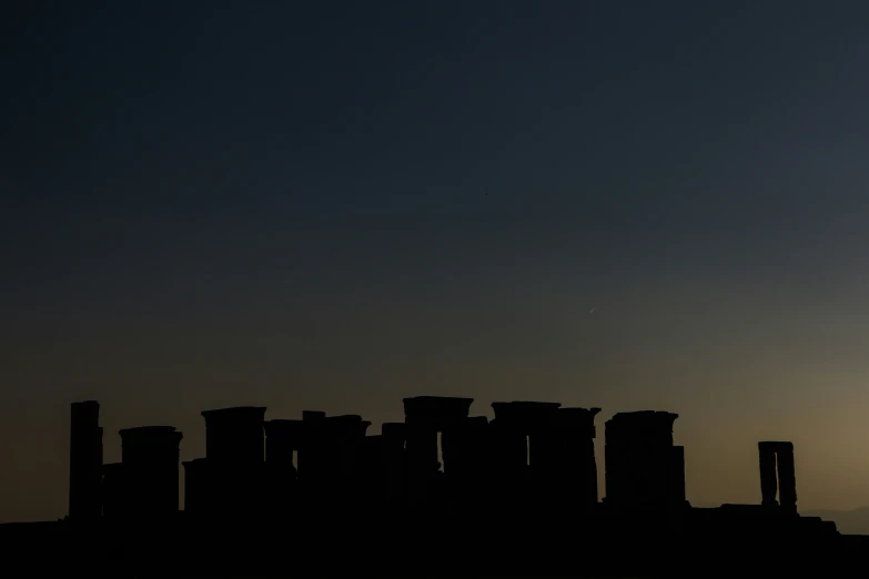 the setting sun over some ruins and structures