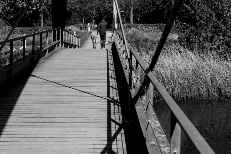 two people walking across a bridge over a river