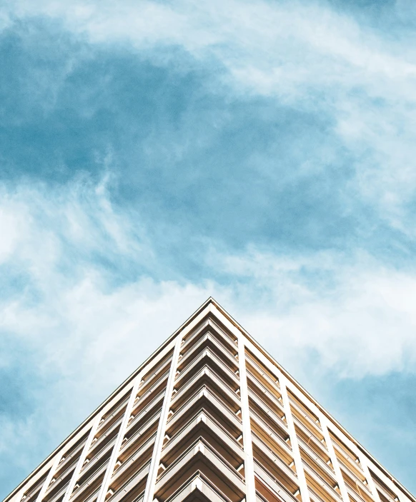 a tall brown building with some white clouds in the background