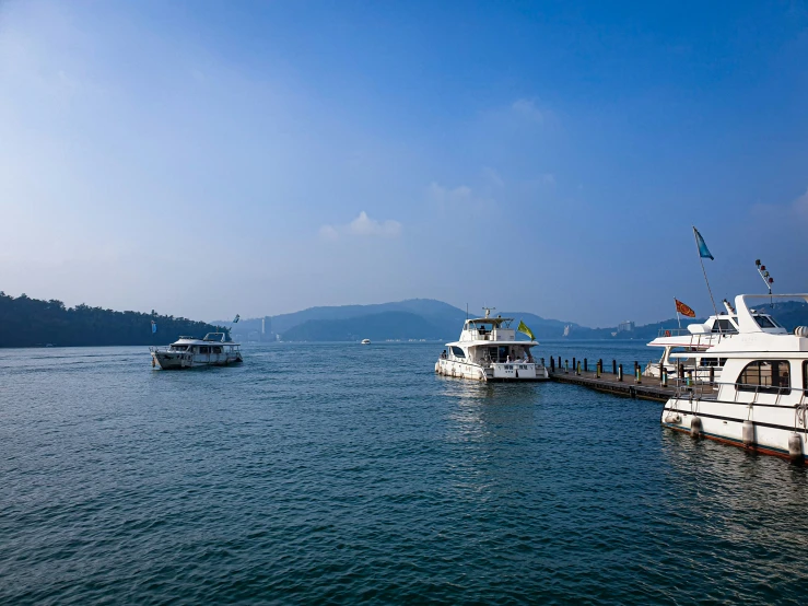 four boats are in the water by a pier