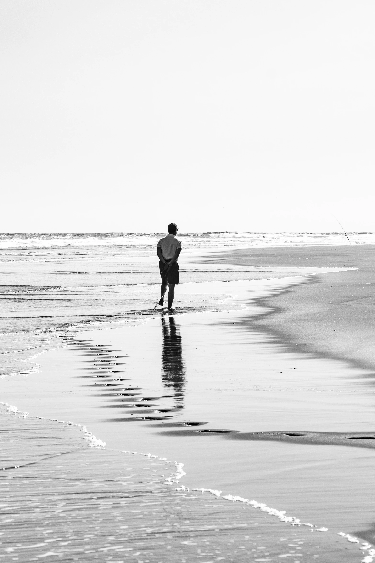 a man standing on top of a wet beach next to the ocean