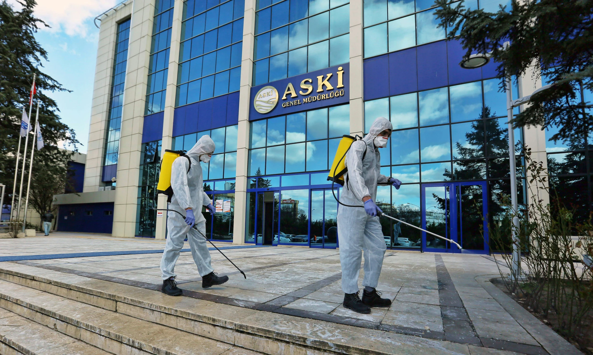 two people in white and yellow are walking with a stick outside of a building