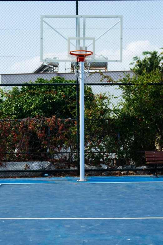 a small basketball court with a blue bench behind it