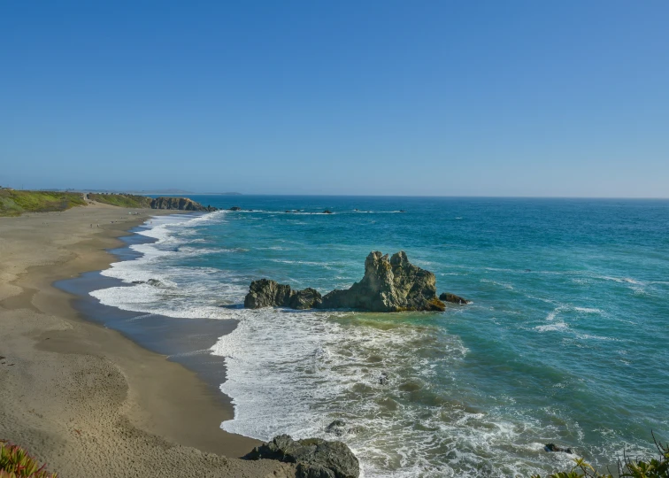 a beach has blue water and waves near the shore