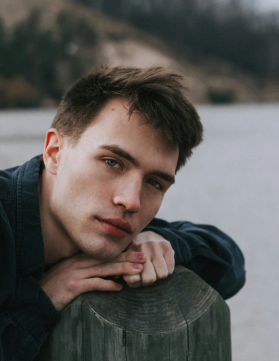 a young man leaning on a post while posing