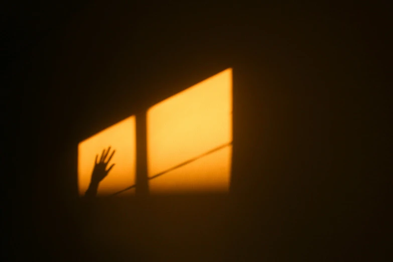 a shadow of someone's hand reaching out a window