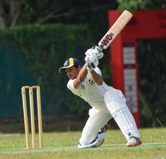 a man in white batting stance by the ground with a bat