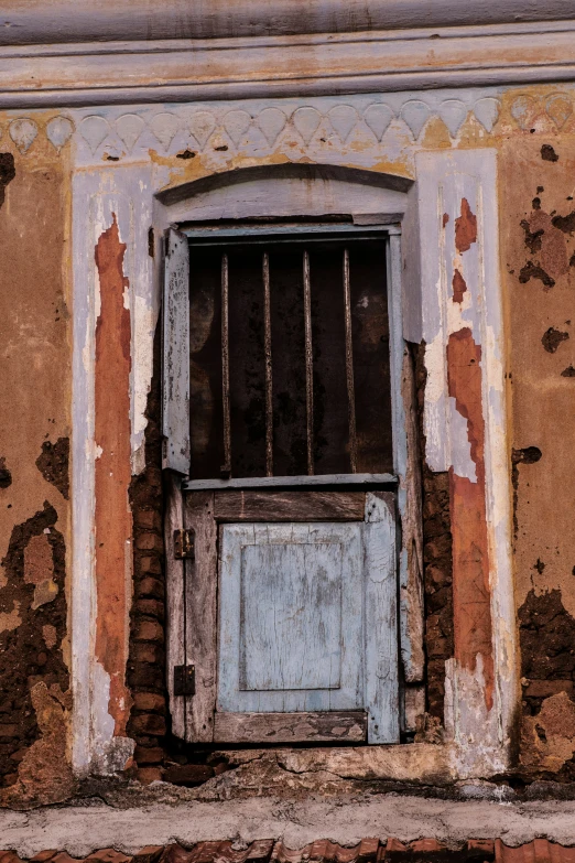 there is a dilapidated wall with bars and a door