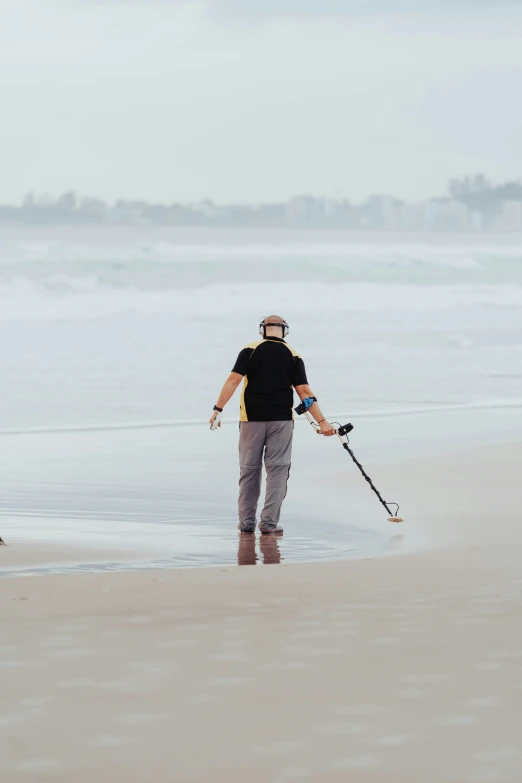 the man walks along the beach carrying his gear