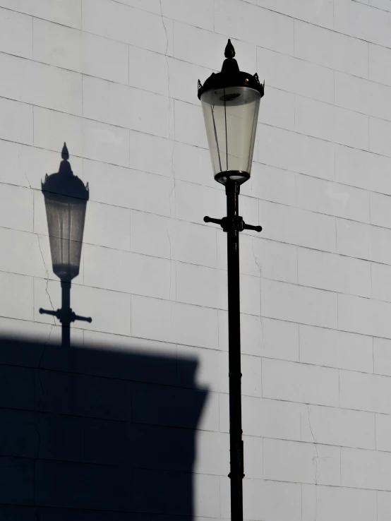 a street lamp casts the shadow against a white building