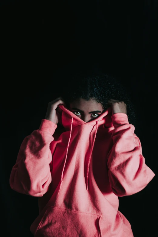 a girl with black hair and wearing a pink hoodie