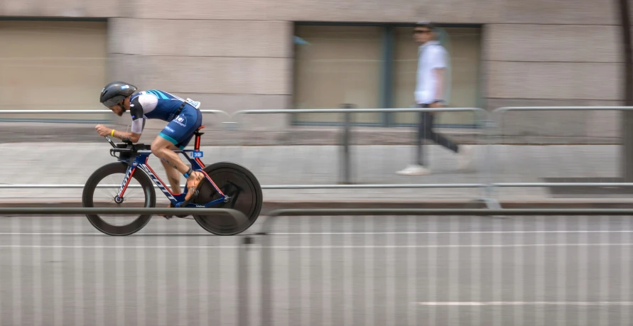 man riding his bike down the street near a barrier