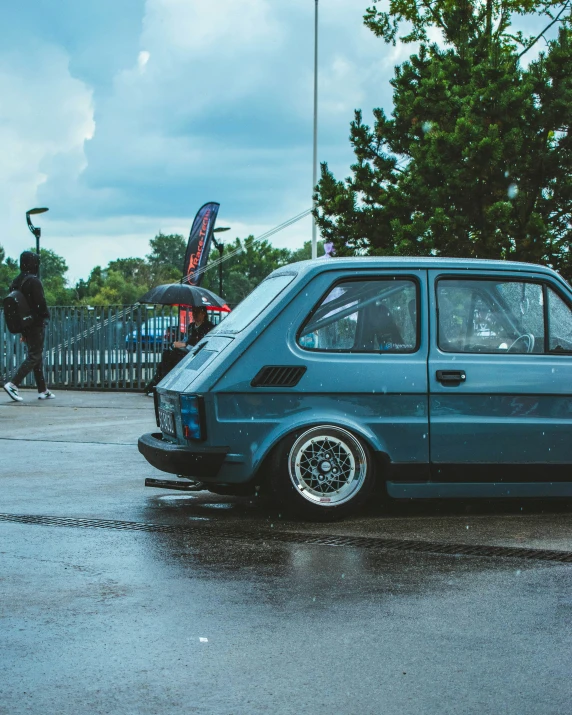 a blue car parked in the rain near a gate