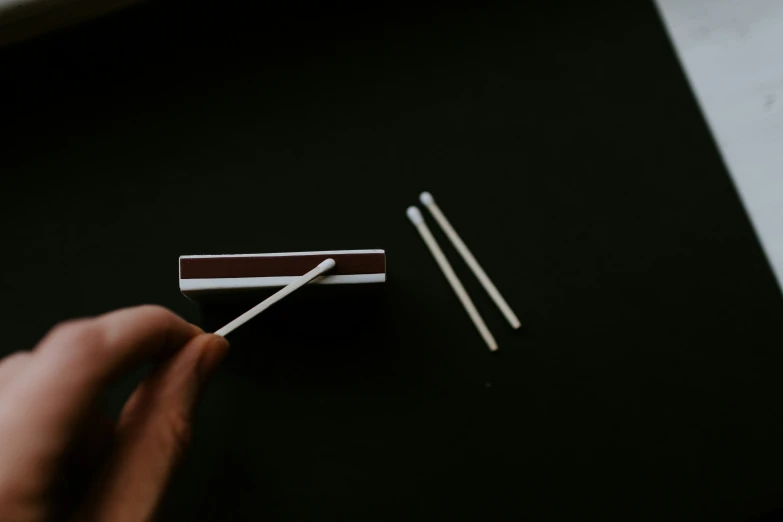 a person holding matchsticks over a black table