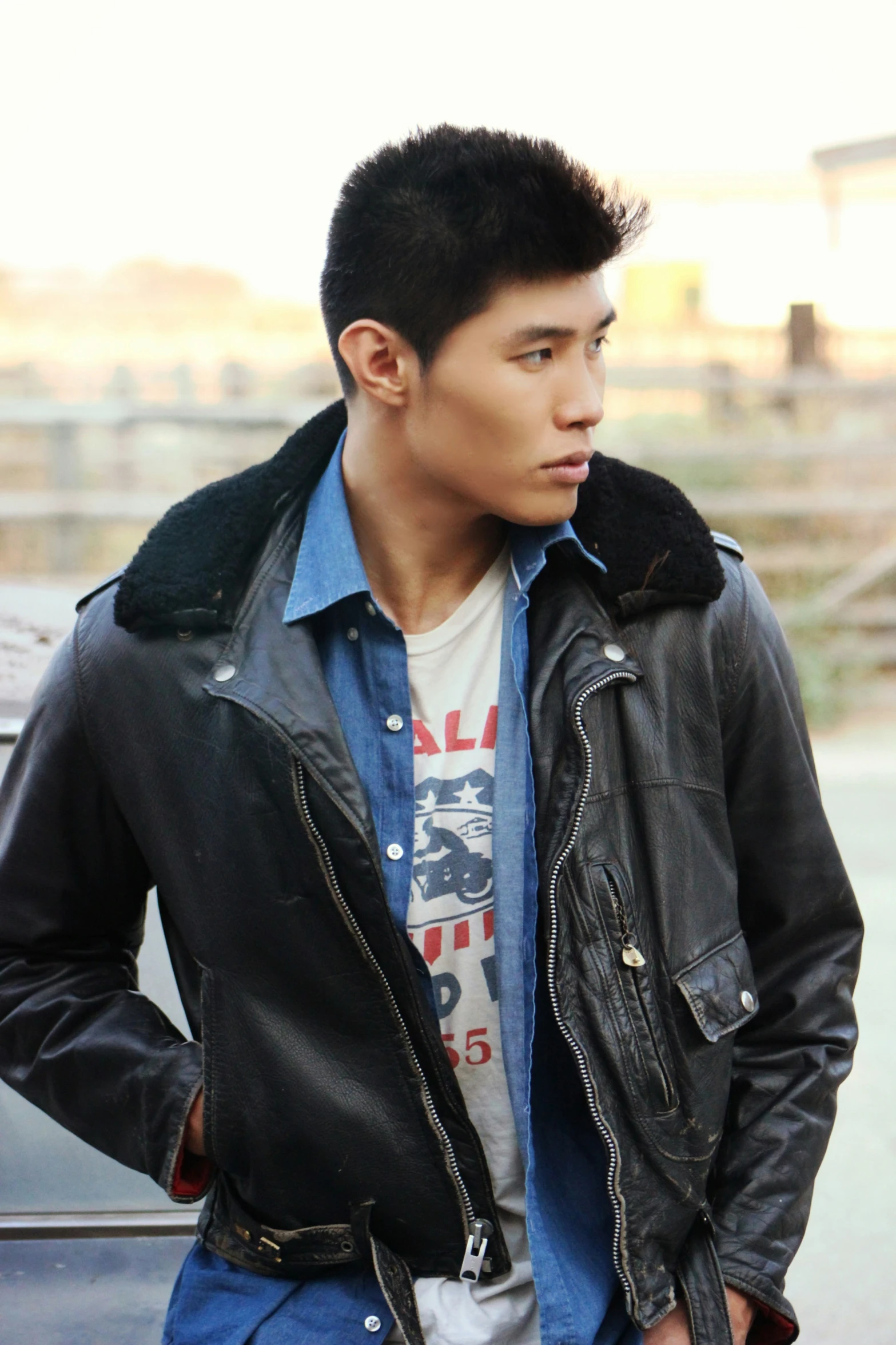 a young man in a leather jacket looking back to the camera