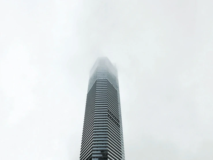 an upward view of the top of the building in the fog