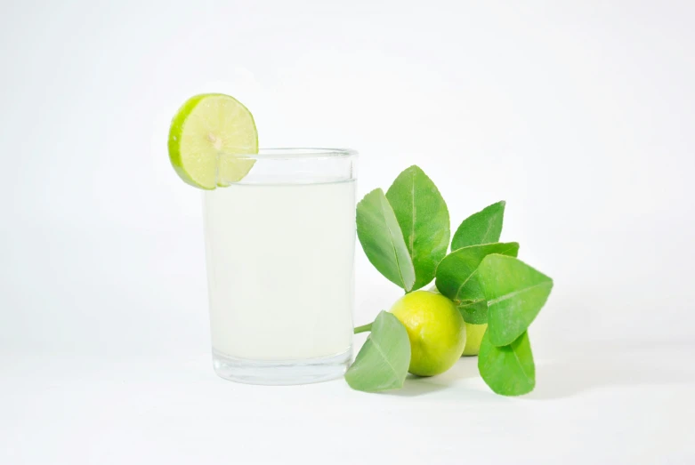 a green lime, lime and a glass filled with water