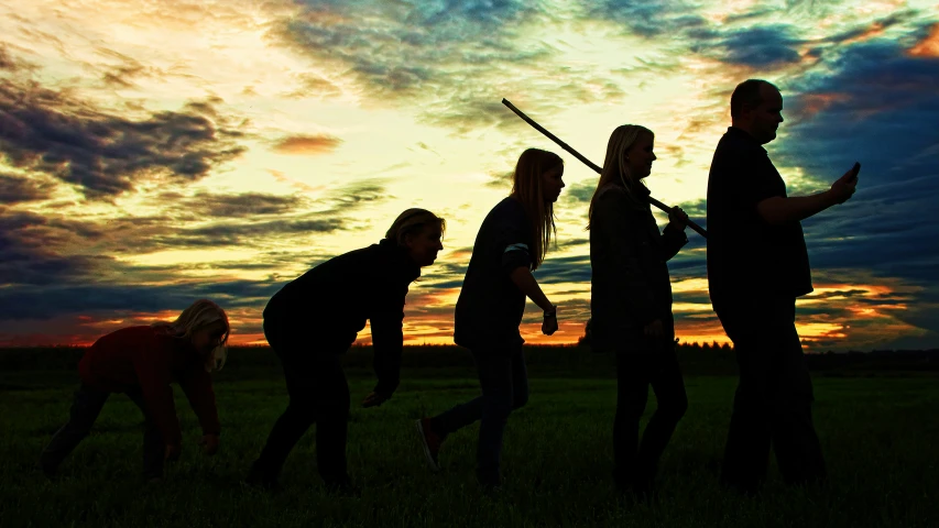 three people holding weapons and standing on a field