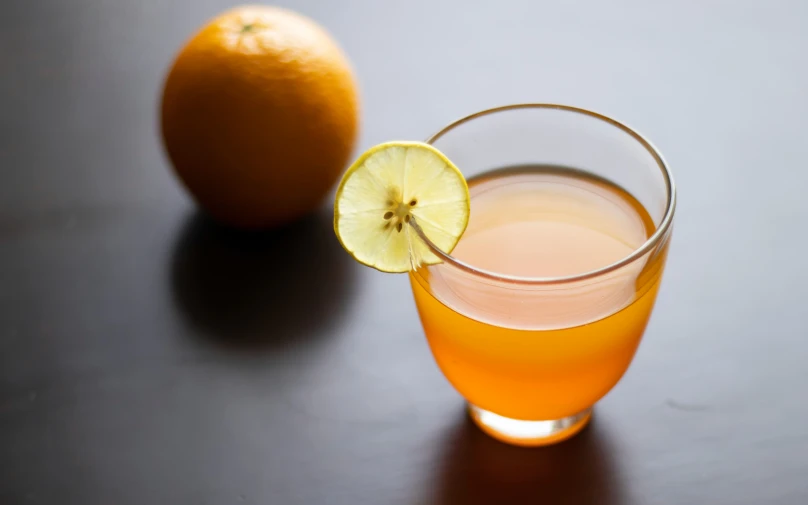 a close up of a glass of orange juice and an orange