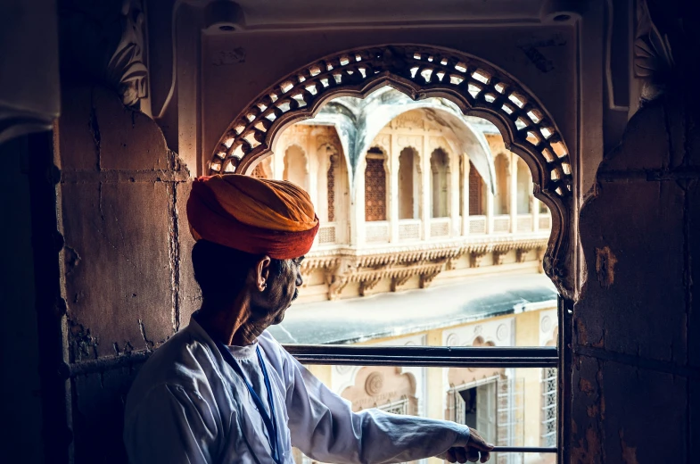 an indian man looks out the window to take in his surroundings