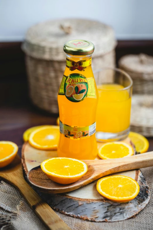 this is a glass and bottle of orange juice with a wooden spoon