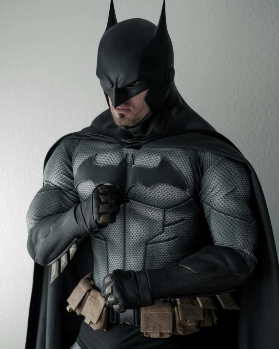 a man dressed as batman is holding onto his glove