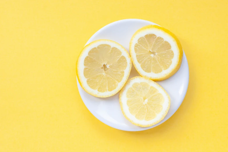 four lemon halves sit on a plate and are sliced