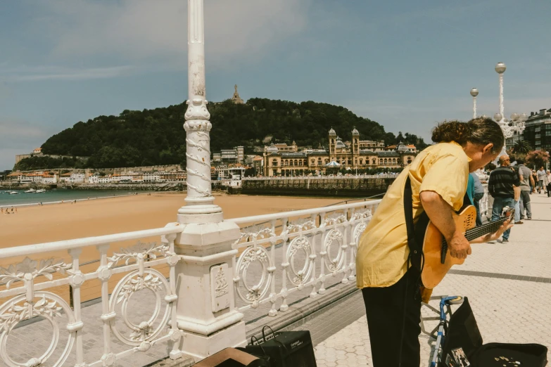 people are standing near the water on a balcony overlooking a beach