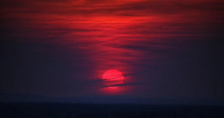 the sun rising behind clouds during sunset