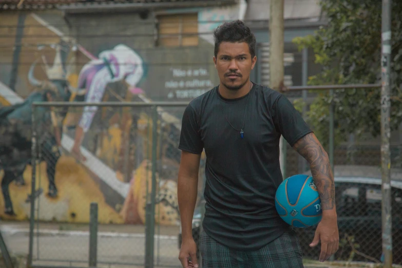 a man carrying a basketball near a fence