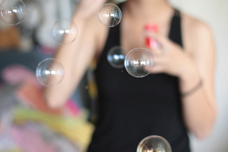 a woman holding a bottle while blowing soap bubbles