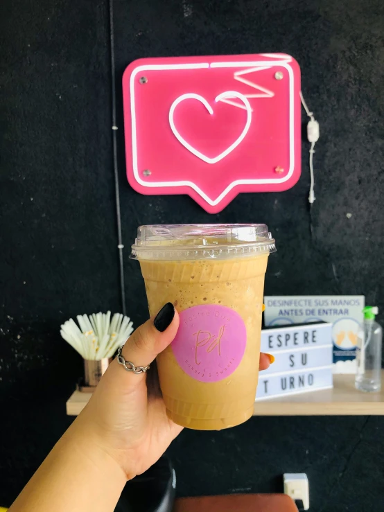 person holds up a cup with coffee in front of a social message bubble sign