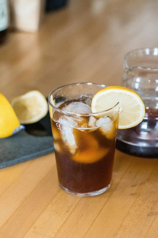 a glass full of ice tea next to a sliced lemon