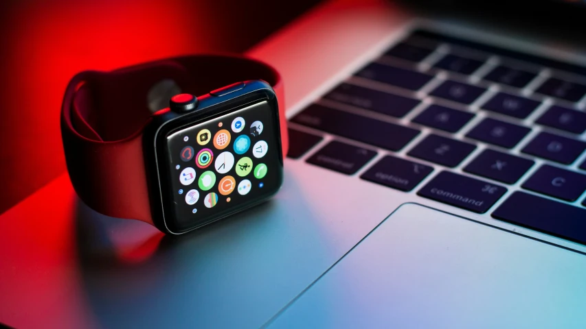 an apple watch on a desk by a laptop