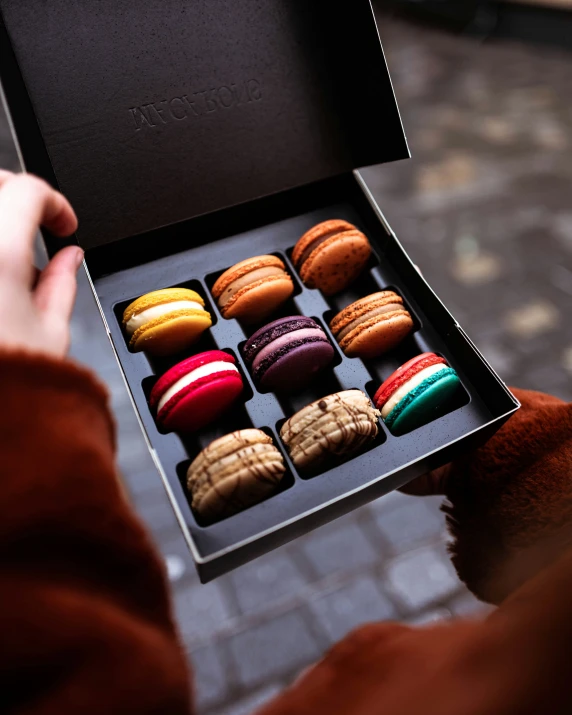 a person holds an open box of colored chocolates