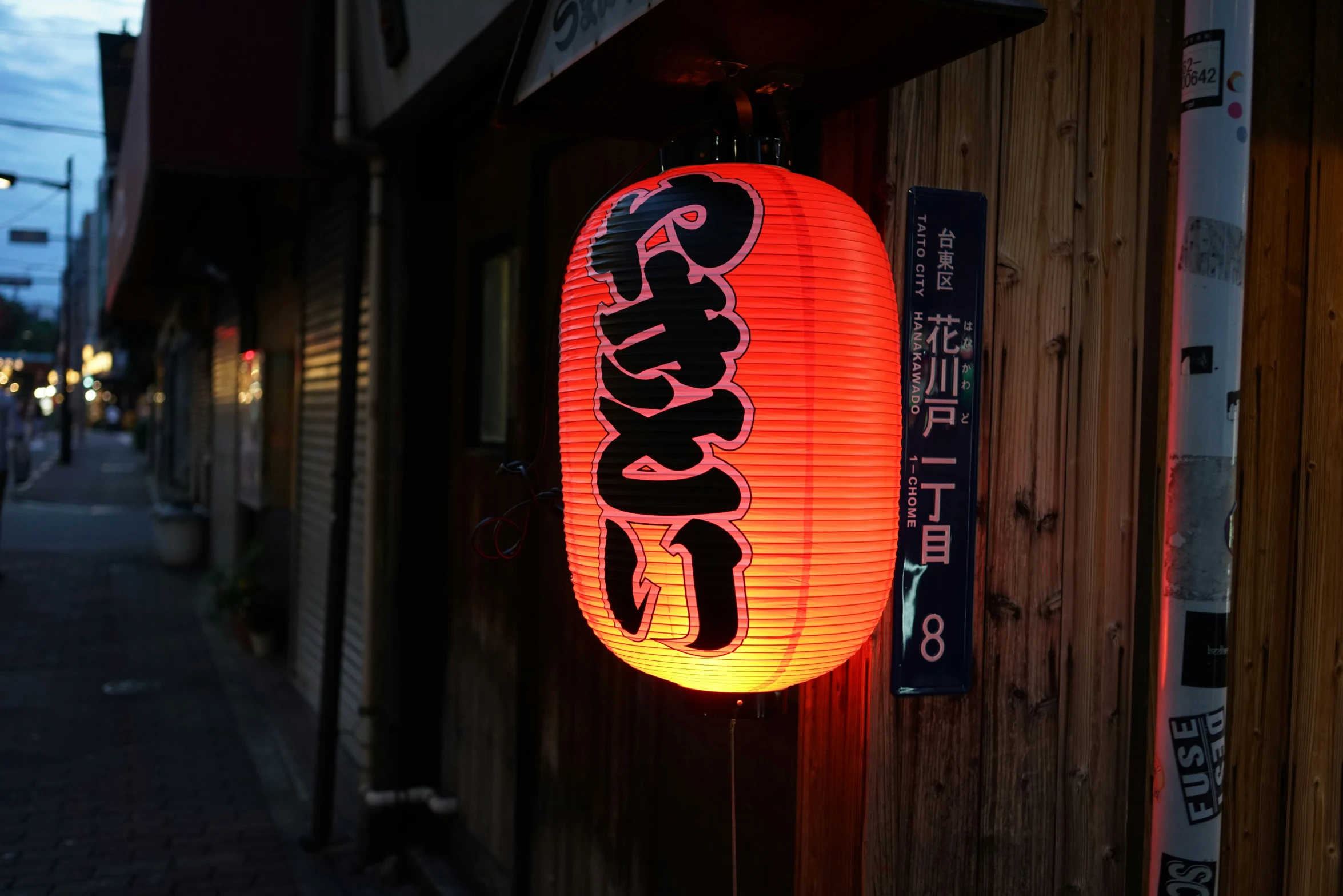 a chinese lamp in a side street next to a wall