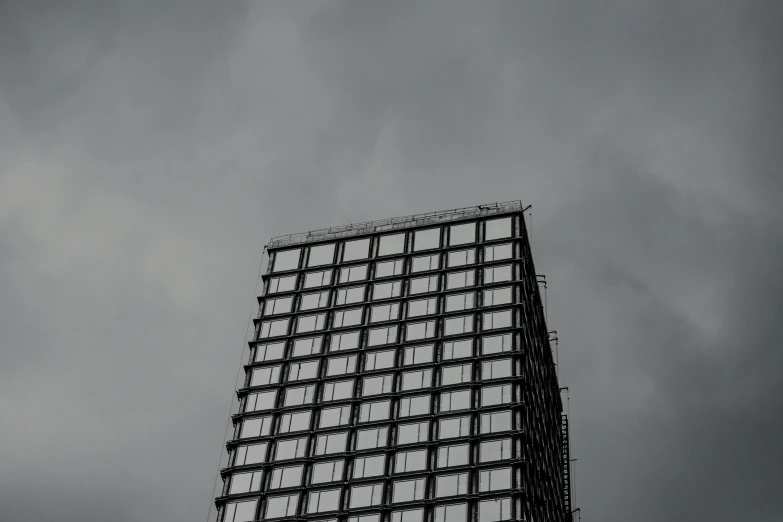 a tall building with lots of windows sitting under clouds