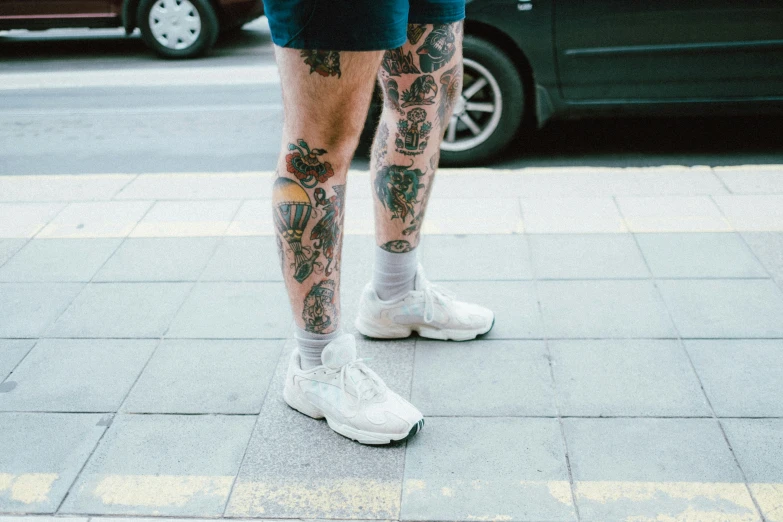 a man with tattoos standing on the side walk