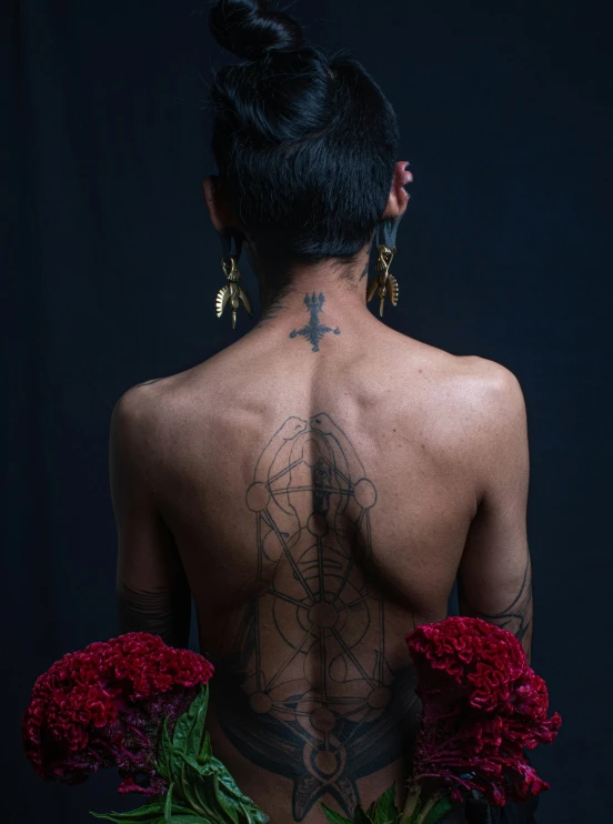 a female with tattoos and flowers on her back