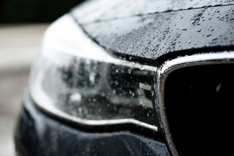 an extreme close up of the hood and chrome of a black vehicle