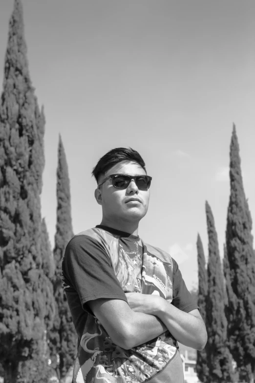 black and white po of man in sunglasses leaning his arms crossed