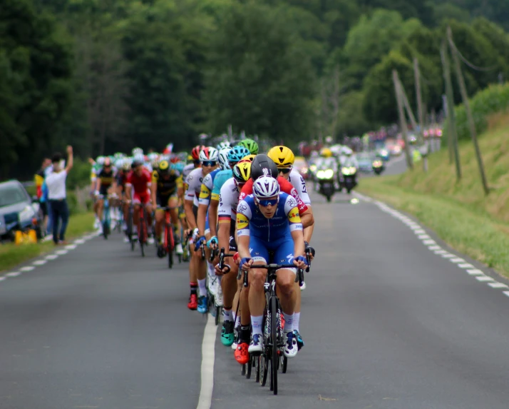 many cyclists are in a bike race going down the road