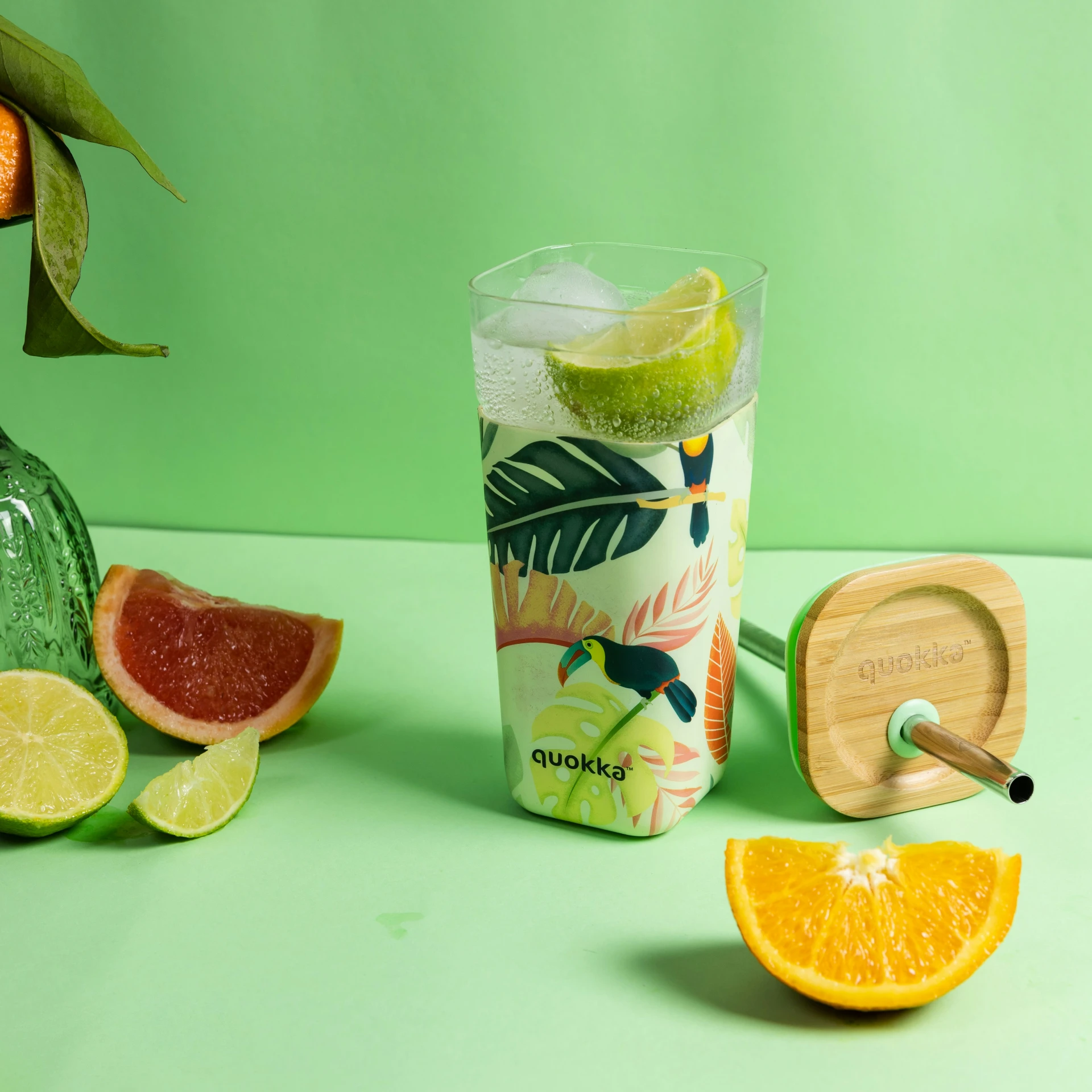 a glass with some slices of orange, lime, and a wooden coaster