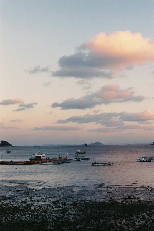 several boats floating in the water near a beach