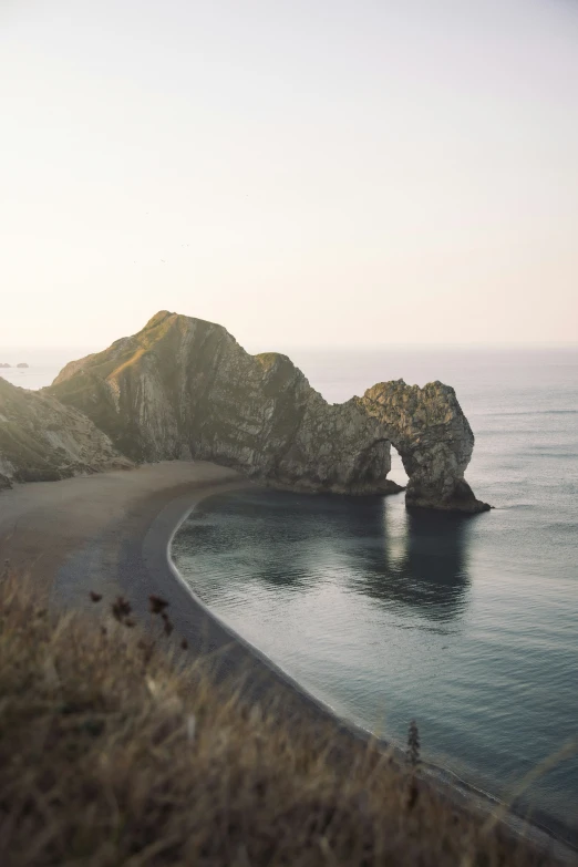 an empty beach with two large rocks on top of it